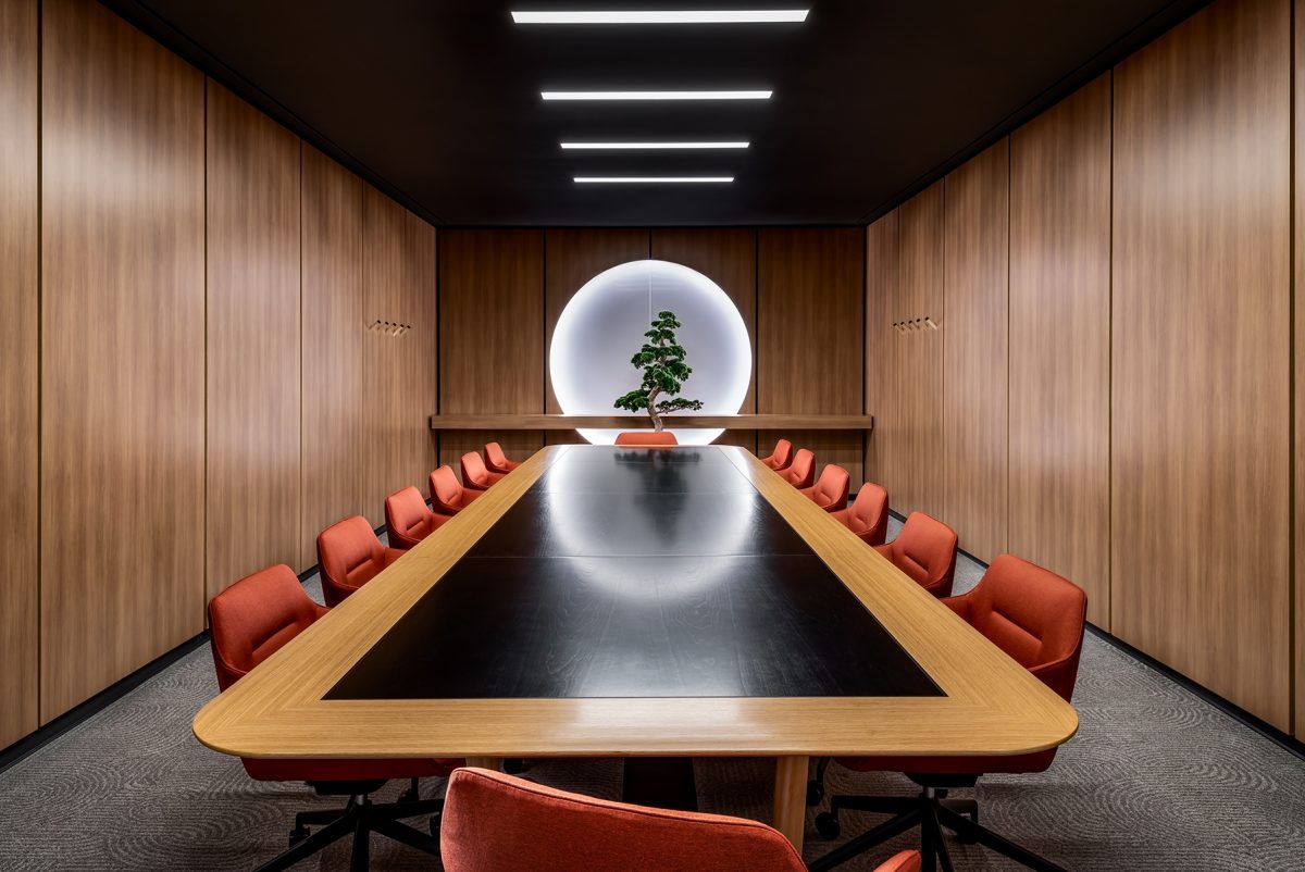 Large meeting room with orange chairs, wood walls and tree feature