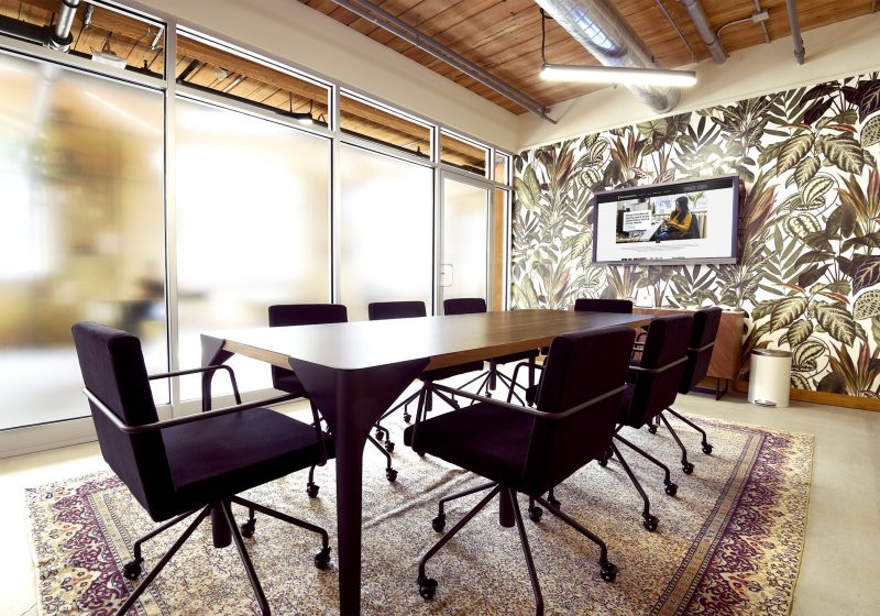 Meeting room with black chairs and floral wallpaper at Workplace One Queen