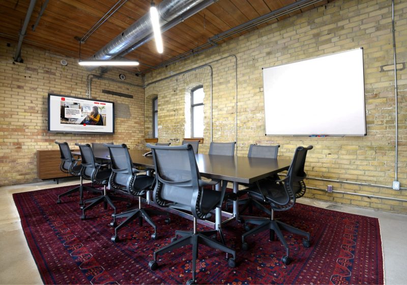 Large meeting room with brick walls and TV at Workplace One Queen